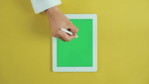 الكتابة والعمل على شاشة الجهاز التقني, استخدام التكنولوجيا و التقنيات الحديثة، مفهوم إدارة المشاريع وانجاز المهام عن بعد، تصوير علوي عامودي ليد رجل عربي سعودي خليجي يرتدي الثوب التقليدي و يستخدم جهاز تابلت بشاشة خضراء فارغة، تصفح مواقع و وسائل التواصل الاجتماعي, كروما