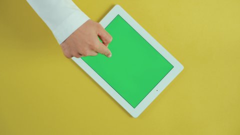 تطبيقات وبرامج الأجهزة اللوحية، استخدام التكنولوجيا و التقنيات الحديثة، مفهوم إدارة المشاريع وانجاز المهام عن بعد، تصوير علوي عامودي ليد رجل عربي سعودي خليجي يرتدي الثوب التقليدي و يستخدم جهاز تابلت بشاشة خضراء فارغة، تصفح مواقع و وسائل التواصل الاجتماعي, كروما