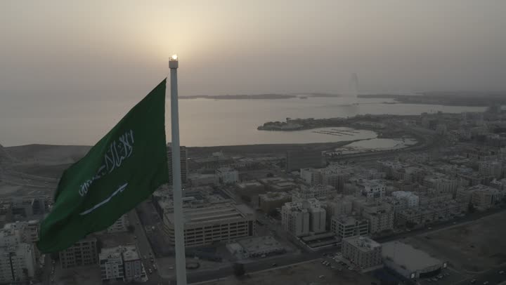 كورنيش جدة البحري، راية التوحيد الخضراء ترفر في السماء، ميدان وشوارع ومعالم جدة المشهورة، تصوير درون لطريق الملك عبد الله المالي في مدينة جدة في المملكة العربية السعودية في وقت الغروب، حركة مرور السيارات، الابراج والمباني السكنية، جمال مدينة جدة