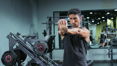 زيادة المرونة وتمديد العضلات، أسلوب الحياة الصحي، إيماءات الحماس و النشاط، المحافظة على التوازن الجسدي، تقوية العضلات ونحت الجسم، مفهوم الرشاقة واللياقة، ممارسة التمارين لشد الجسد، شاب عربي خليجي سعودي يرتدي الملابس الرياضية يقوم بممارسة التمرينات الرياضية