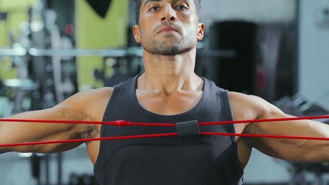 Increasing flexibility and stretching muscles, maintaining physical fitness, the importance of sports for building a strong body, an Arab Gulf Saudi man practicing an exercise to improve body posture and balance, a young Arab Gulf Saudi man wearing sportswear training with a resistance band, a healthy lifestyle.