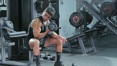 Gestures of strength and confidence, following a healthy diet, training to master weightlifting, monitoring muscle contraction and relaxation, physical activity to maintain physical fitness, a young Arab Gulf Saudi man performing exercises using a barbell, bodybuilding.