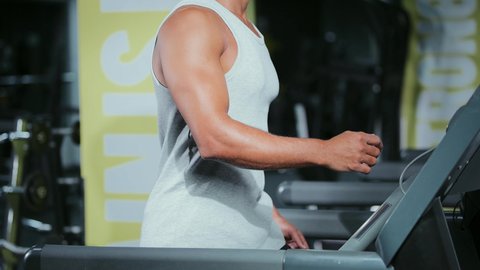 Taking care of the body and physical health, using sports equipment, engaging in enjoyable recreational activities, sports club, practicing warm-up exercises, a young Arab Gulf Saudi man wearing sports clothes walking on the treadmill.