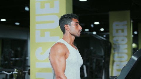 Sports club, practicing warm-up exercises, maintaining health and physical fitness, a young Arab Gulf Saudi man wearing sportswear walking on the treadmill, engaging in enjoyable recreational activities, using sports equipment.