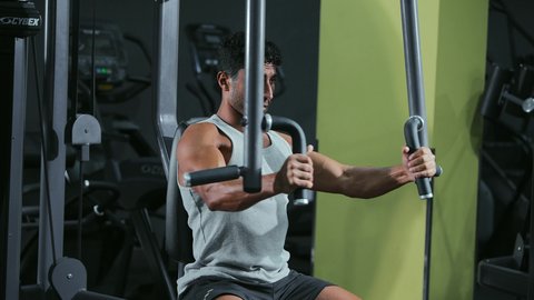 A healthy lifestyle, strengthening the nerves and muscles, using sports equipment, the importance of sports for building a strong body, a young Arab Gulf Saudi man wearing sportswear practicing an exercise to strengthen the chest, arms, and shoulders on the parallel bars.