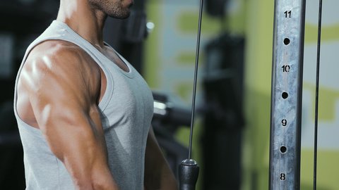 Weight loss and burning excess fat, using sports equipment, a healthy and beneficial lifestyle, the concept of fitness and agility, an activity to strengthen muscles, a young Arab Gulf Saudi man wearing sportswear practicing back exercises on a lat pulldown machine.