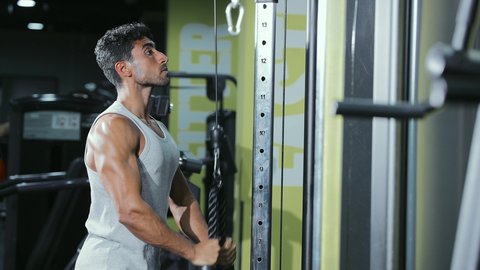 حرق السعرات والتخلص من الوزن الزائد، استخدام الأجهزة الرياضية،  نمط حياة صحي ومفيد، مفهوم اللياقة والرشاقة، نشاط لتقوية العضلات، شاب عربي خليجي سعودي يرتدي الزي الرياضي يقوم بممارسة تمارين الظهر على آلة السحب العلوي