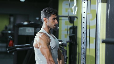 استخدام الأجهزة الرياضية، حرق الدهون وتقليل الوزن،  نمط حياة صحي ومفيد، مفهوم اللياقة والرشاقة، نشاط لتقوية العضلات، شاب عربي خليجي سعودي يرتدي الزي الرياضي يقوم بممارسة تمارين الظهر على آلة السحب العلوي