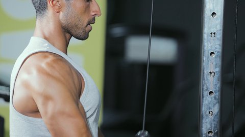 Burning fat and losing weight, a healthy and beneficial lifestyle, the concept of fitness and agility, an activity to strengthen muscles, using sports equipment, a young Arab Gulf Saudi man wearing sportswear practicing back exercises on a pull-up machine.
