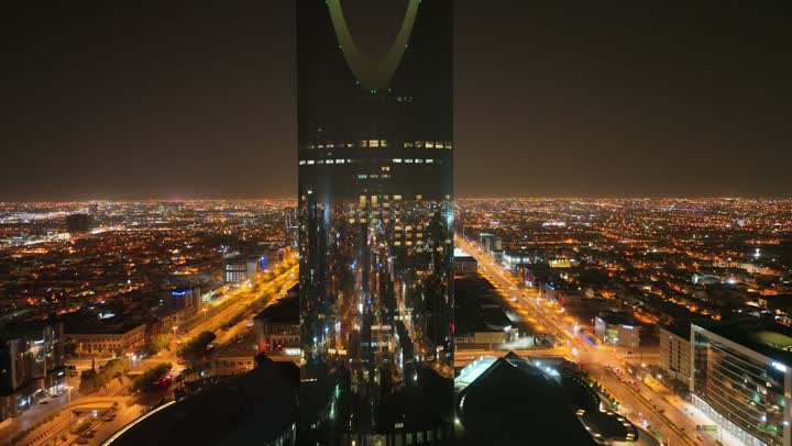 النمو والتطور والتقدم العمراني،  تصوير درون لبرج المملكة الشهير المضاء في وقت الليل، المباني والمعالم التجارية المشهورة في المملكة العربية السعودية، الفن الهندسي المعماري على الطراز المتطور والحديث للأبراج وناطحات السحاب في مدينة الرياض