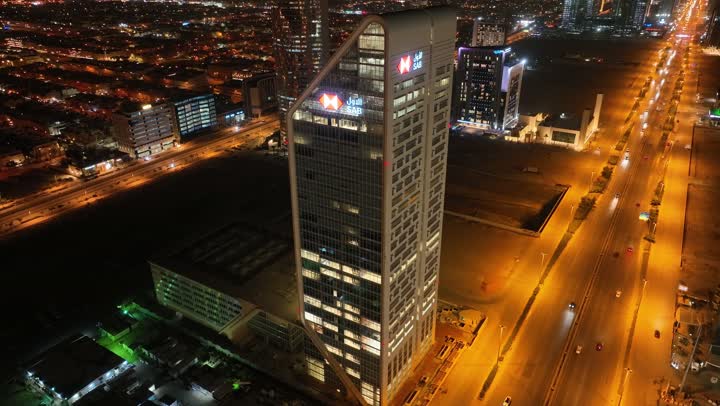 الفن الهندسي المعماري على الطراز المتطور للأبراج وناطحات السحاب في مدينة الرياض، نمط الحياة في العاصمة، النمو والتطور والتقدم العمراني،  تصوير درون لبرج بنك ساب في وقت الليل، المباني والمعالم التجارية المشهورة في المملكة العربية السعودية، طريق الملك فهد