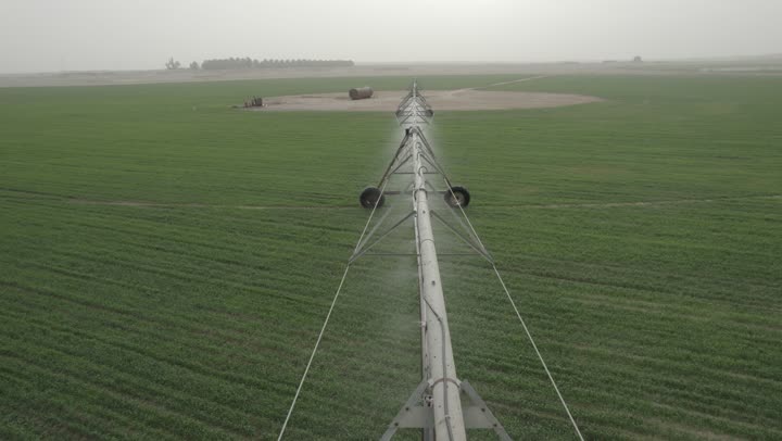 الات ومعدات الري في حقل زراعي بالمملكة العربية السعودية، الاراضي والحقول الزراعية، الاعتناء والاهتمام بالاشجار والنباتات الخضراء، تصوير درون لاذرع الري المحوري في الحقول الزراعية، الرشاشات الحديثة للمياه