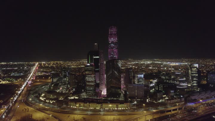 The lifestyle in the capital, urban growth and development in Saudi Arabia, drone photography of the illuminated financial buildings and towers in Riyadh at night, the architectural art of the famous buildings and skyscrapers in the Kingdom, achieving economic and commercial renaissance.