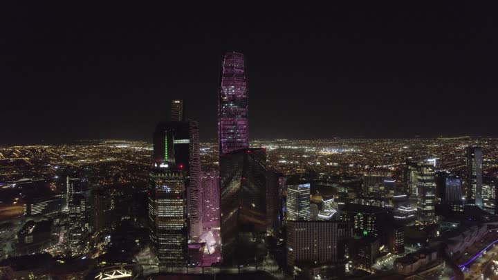 تحقيق النهضة الاقتصادية والتجارية، نمط الحياة في العاصمة، النمو والتطور العمراني في السعودية، تصوير درون للمنشآت والأبراج المالية في مدينة الرياض المضاءة في وقت الليل، الفن الهندسي المعماري للمباني وناطحات السحاب المشهورة في المملكة