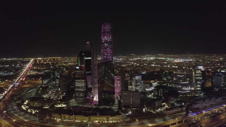 The lifestyle in the capital, urban growth and development in Saudi Arabia, drone photography of the illuminated financial buildings and towers in Riyadh at night, the architectural art of the famous buildings and skyscrapers in the Kingdom, achieving economic and commercial renaissance.