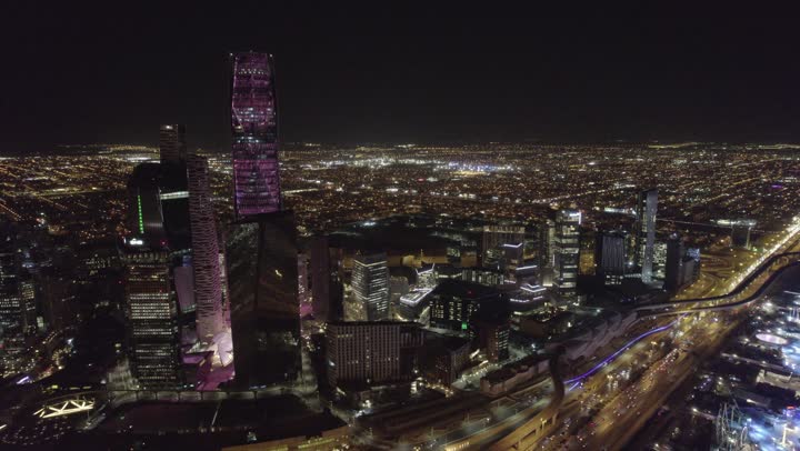 تحقيق النهضة الاقتصادية والتجارية، نمط الحياة في العاصمة، النمو والتطور العمراني في السعودية، تصوير درون للمنشآت والأبراج المالية في مدينة الرياض المضاءة في وقت الليل، الفن الهندسي المعماري للمباني وناطحات السحاب المشهورة في المملكة