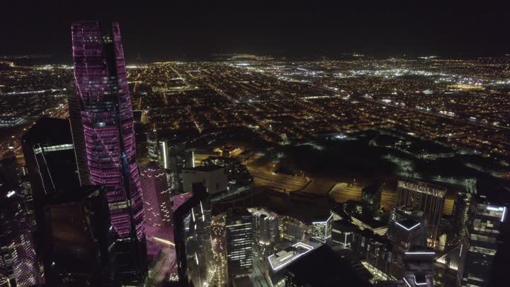 The lifestyle in the capital, urban growth and development in Saudi Arabia, drone photography of the illuminated financial buildings and towers in Riyadh at night, the architectural art of the famous buildings and skyscrapers in the Kingdom, achieving economic and commercial renaissance.