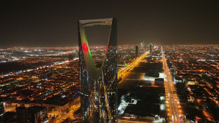 النمو والتطور والتقدم العمراني،  تصوير درون لبرج المملكة الشهير المضاء في وقت الليل، المباني والمعالم التجارية المشهورة في المملكة العربية السعودية، الفن الهندسي المعماري على الطراز المتطور والحديث للأبراج وناطحات السحاب في مدينة الرياض