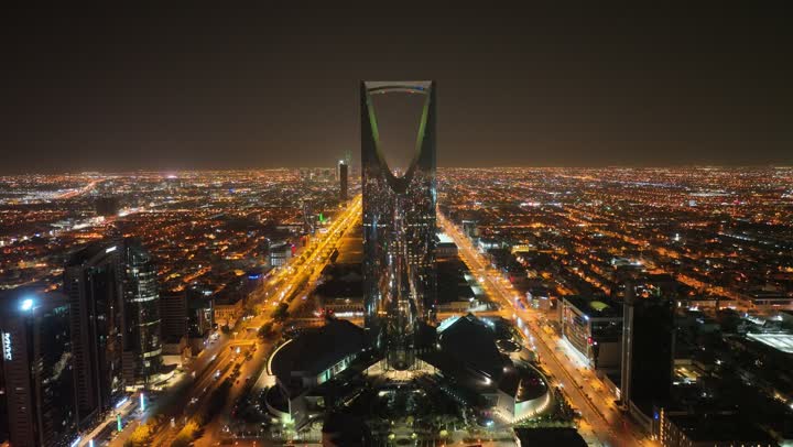 النمو والتطور والتقدم العمراني،  تصوير درون لبرج المملكة الشهير المضاء في وقت الليل، المباني والمعالم التجارية المشهورة في المملكة العربية السعودية، الفن الهندسي المعماري على الطراز المتطور والحديث للأبراج وناطحات السحاب في مدينة الرياض