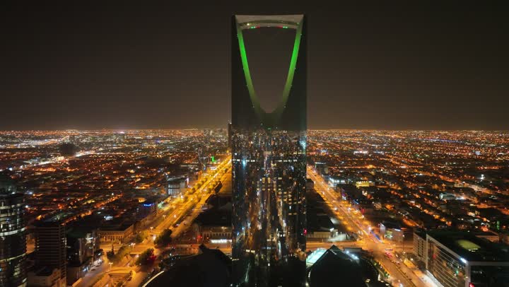 النمو والتطور والتقدم العمراني،  تصوير درون لبرج المملكة الشهير المضاء في وقت الليل، المباني والمعالم التجارية المشهورة في المملكة العربية السعودية، الفن الهندسي المعماري على الطراز المتطور والحديث للأبراج وناطحات السحاب في مدينة الرياض