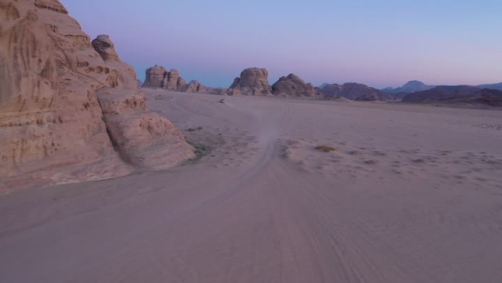 The use of modern vehicles for fast land transportation, driving on rough roads and sand dunes, traveling through the deserts of Saudi Arabia, means of transportation and communication, the desert nature and dry environment, drone photography for adventures and safari trips in the Al-Ula desert.