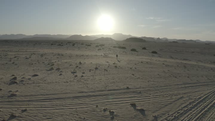 Historical archaeological tourist landmarks, desert and mountainous nature, natural rock formations in Al-Ula's Madain Saleh in the Kingdom of Saudi Arabia, drone footage of a man running in the desert, the mountains and rock formations in Al-Ula.