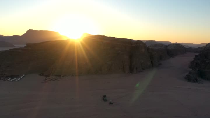 A youth camping trip in the deserts of the Kingdom of Saudi Arabia, tourist camps in the wilderness, drone photography of a group of tents amidst the sands, Bedouin life in the desert, the terrain and soft golden dunes, and thorny plants.