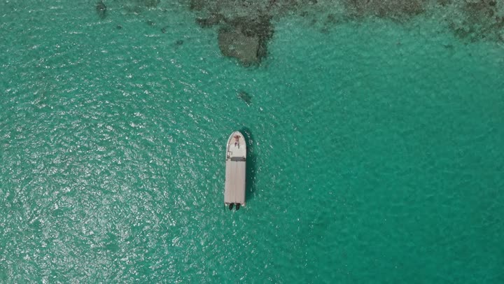 Enjoyment on the coastal beaches, distinctive landscapes, famous tourist areas, the calm waves in the waters of the Red Sea in the Kingdom of Saudi Arabia, the famous coastal places and landmarks, aerial drone photography of a man spending time on a ship in the middle of the Red Sea.