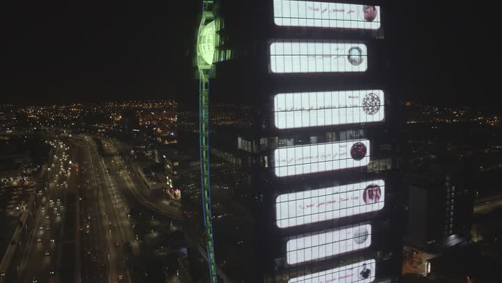 The largest advertising display screen in the world, the development of neighborhoods and roads in the country, the screen tower in the city of Jeddah, car traffic in the streets at night, urban growth and progress in Saudi Arabia, the architectural engineering art of towers and buildings, advanced digital electronic screens.
