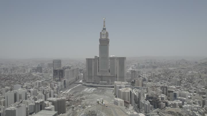 مقصد المسلمين من مختلف البلدان، في مكة المكرمة برج الساعة، مكان ومعلم ديني مقدس في المملكة العربية السعودية, تصوير درون جوي مقرب للفن الهندسي المعماري للأبراج وناطحات السحاب، التقدم والنمو العمراني للفنادق والمباني المطلة على الحرم المكي الشريف