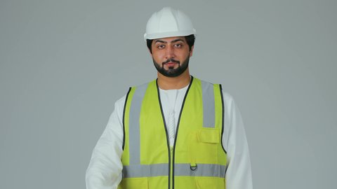 Youth professions and jobs in the United Arab Emirates, a mark of quality and excellence, the concept of architectural constructions, a portrait of an Emirati Gulf Arab engineer wearing a kandura, helmet, and safety vest, raising his thumb up in gestures of admiration, white background.