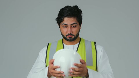 مفهوم الهندسة والانشاءات المعمارية، الوقوف بأيدي متقاطعه، بورتريه لمهندس عربي خليجي إماراتي يرتدي الكندورة والسترة الخاصة بالعمل ينظر بإيماءات السرور و الثقه بالنفس، العمل في القطاع الهندسي، مهن ووظائف اماراتية، الإعمار بسواعد أبناء الوطن، خلفية بيضاء