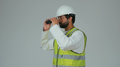 توسيع زاوية النظر، الإشراف على المشاريع الهندسية، القطاع الهندسي في الإمارات، بورتريه لمهندس عربي خليجي إماراتي يرتدي الكندورة والخوذة وسترة الحماية ينظر عبر منظار ثنائي العينين، التخطيط والبحث للمستقبل، خلفية بيضاء