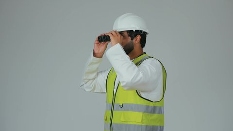 Improving vision range, supervising engineering projects, the engineering sector in the UAE, a portrait of an Arab Gulf Emirati engineer wearing a kandura, helmet, and safety vest looking through binoculars, planning and research for the future, white background.
