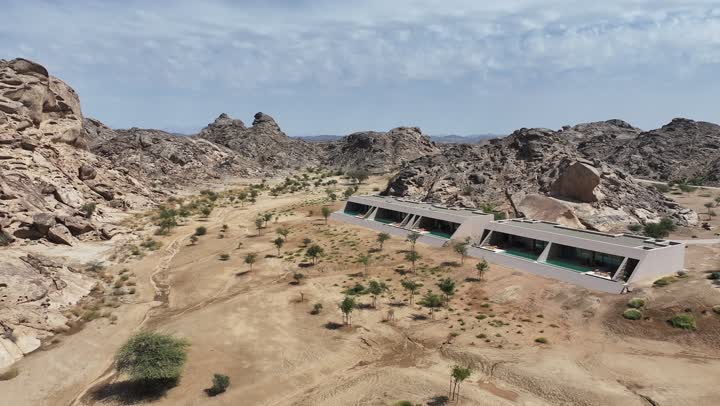 مناظر وظواهر طبيعية، أملج الساحلية في السعودية، نسيج الصخور على وجه الجبل، الاهتمام بالزراعة في مناطق الكثبان الرملية، منظر بانورامي للجبال الصخرية الصحراوية، تصوير درون   لجبال من التشكلات الصخرية في صحراء المملكة العربية السعودية مع خيم باللون الأسود