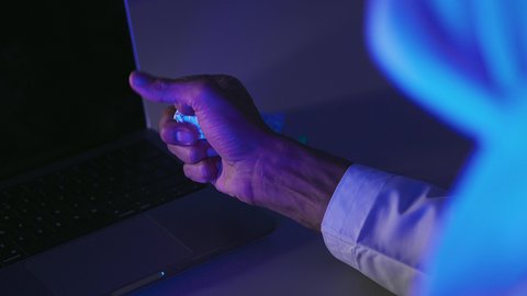 Failure at work, a close-up shot of the hand of a Saudi Arabian Gulf man in front of a laptop with a bunch of crumpled papers beside him, searching for ideas and plans, struggling with writing and blogging, trying to find solutions to create a story.