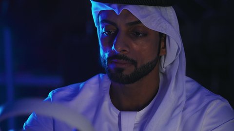 الاستفادة من التكنولوجيا الحديثة، مفهوم الإصغاء والاستماع، إستخدام تقنية الهيدفون، قضاء أوقات ممتعة بسماع الاغاني والمقاطع الصوتية، تصوير مقرب لرجل عربي خيجي اماراتي يرتدي الكندورة والغترة يقوم بوضع سماعة الرأس