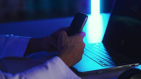 Mobile services and applications, browsing social media, technological development and progress, modern and advanced technical devices, a close-up shot of the hand of a Saudi Arabian Gulf man sitting in front of a laptop using a mobile phone.