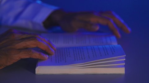 مفهوم الثقافة والتعلم الذاتي، قضاء أوقات الفراغ بممارسة هواية المطالعة, قراءة القصص والروايات الممتعة, تصوير مقرب لأيدي رجل عربي خليجي سعودي يمسك بيده الكتاب, تنمية الذخيرة الثقافية