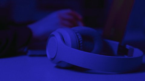 قضاء أوقات ممتعة بسماع الاغاني والمقاطع الصوتية، مفهوم الإصغاء والاستماع، استخدام التكنولوجيا الحديثة، استعمال تقنية الهيدفون، تصوير مقرب ليد امرأة عربية خيجية سعودية  ترتدي العباءة تقوم بالنقر على الحاسب المحمول و بجانبها سماعات الهيدفون