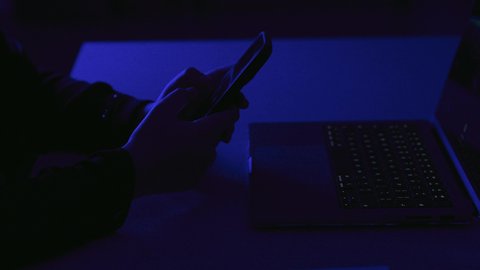 تصفح مواقع التواصل الاجتماعي، مشاهدة الافلام والفيديو، تصوير مقرب ليد امراة عربيه خليجيه سعودية تستخدم الهاتف المحمول تجلس امام الحاسوب المحمول تقوم بمحادثة كتابية ، نقل البيانات والملفات بين الجهازين، التسويق للتطبيقات الالكترونية