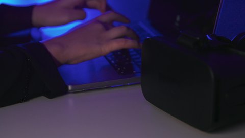 استخدام الأجهزة التكنولوجية والتقنيات الحديثة, محاكاة العالم الخيالي, تصوير  مقرب لايدي امرأة عربية خليجية سعودية  تقوم بإنجاز العمل على جهاز الحاسوب المحمول وبجانبها نظارة الفي ار,النقرعلى لوحة المفاتيح