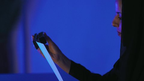 Reviewing work-related documents, following up on plans and projects, organizing and arranging data, reading notes and information, a close-up side shot of a Saudi Arabian Gulf woman wearing a hijab holding a stapler in her hand gathering a bunch of blank papers together.