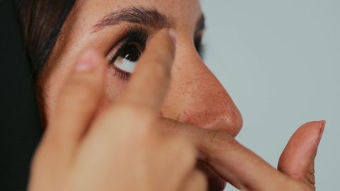 المساعدة على الرؤية الواضحة، تصحيح النظر وطب العيون، مفهوم العدسات اللاصقة الطبية التجميلية، بورتريه مقرب لامراة عربية خليجية سعودية محجبة تضع العدسات التجميلية في عينها، خلفية رمادي