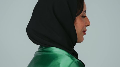 المشاركة بالاحتفال بذكرى اليوم الوطني، الاعتزاز بالراية العمانية،إيماءات الفخر بالانتماء للبلاد، بورتريه لمهندسة عربية خليجية عمانية ترتدي الحجاب والعباءة السوداء وسترة الحماية  تحمل علم السلطنة على كتفها، خلفية رمادية