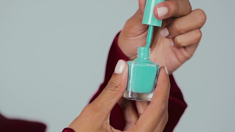 مفهوم الأنوثة والنعومة , خبيرة لمستحضرات التجميل النسائية،  بورتريه لسيدة عربية خليجية سعودية سمراء ترتدي العباءة والحجاب تقوم بوضع طلاء الاظافر باللون التركوازي ، التسويق لمنتجات الميك اب، خلفية رمادية