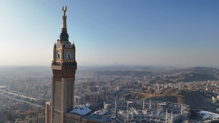 The Clock Tower and modern architectural buildings, aerial drone photography of the city of Mecca in the Kingdom of Saudi Arabia, performing the rituals of Hajj and Umrah, Islamic religious sites and landmarks, modern architectural engineering art for hotels, attractions and drawing Muslims from all over the world.