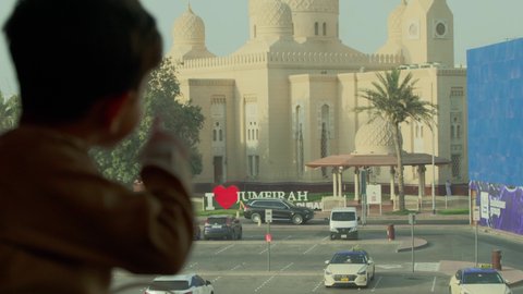 أماكن لأداء العبادة والتقرب إلى الله تعالى، تأمل معالم الوطن، الفن الهندسي المعماري للمساجد في الإمارات، تصوير مقرب من الخلف لولد عربي خليجي اماراتي يرتدي الكندورة يقوم بالنظر إلى المسجد