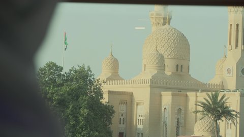 أماكن لأداء العبادة والتقرب إلى الله تعالى، الاناقة والاهتمام بالمظهر الخارجي، تصوير مقرب من الجانب لرجل عربي خليجي اماراتي يرتدي الكندورة والغترة الاماراتية ييقف مع ابنه ويقوم بالنظر إلى المسجد، الفن الهندسي المعماري للمساجد في الإمارات