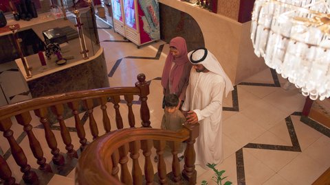 قضاء الأوقات الممتعة مع الابناء, تقديم الاهتمام والعناية للاولاد، أنشطة ترفيهية مسلية, الاستمتاع بالأجواء العائلية في الخارج, عائلة عربية خليجية اماراتية يرتدون الزي التقليدي الاماراتي يصعدون على سلم خشبي في إحدى المطاعم الفاخرة